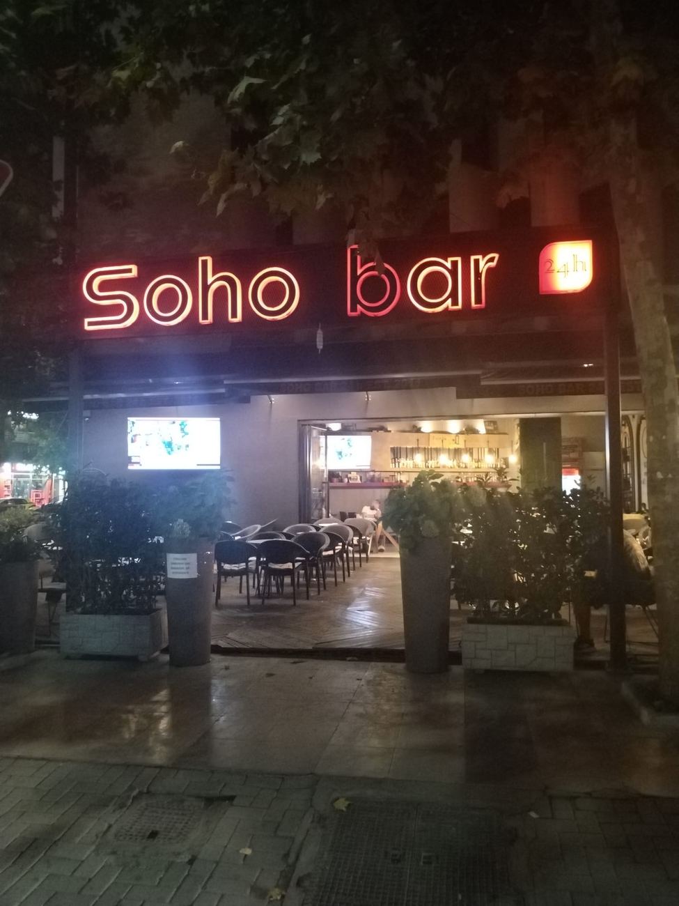 The outdoor seating of SOHO BAR under the plane trees in the evening